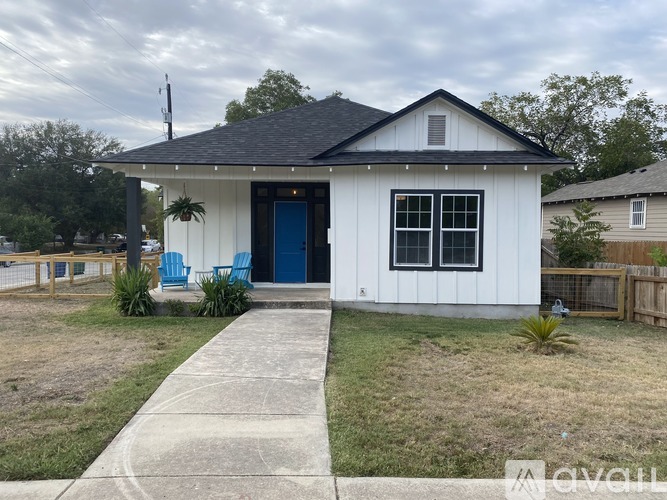 A small white house with a black roof and a blue door.