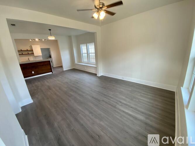 A spacious room with a ceiling fan and wooden flooring.