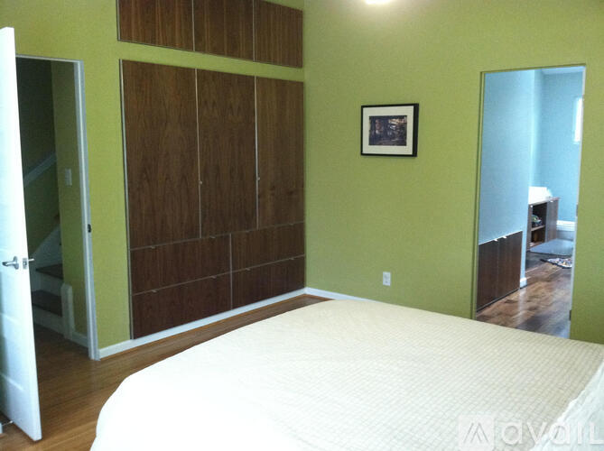 A bedroom with a bed, wooden closet doors, and a picture on the wall.
