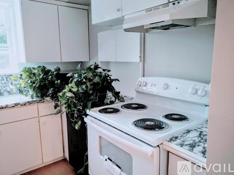 A white stove top oven with a black burner is in a kitchen with white cabinets.