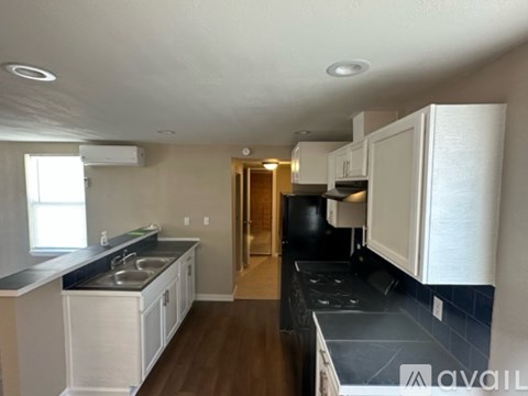 A kitchen with white cabinets and black countertops is available for rent.