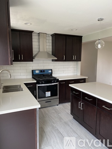 A kitchen with dark brown cabinets and a white countertop.