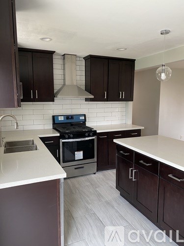 A kitchen with dark brown cabinets and a white countertop.