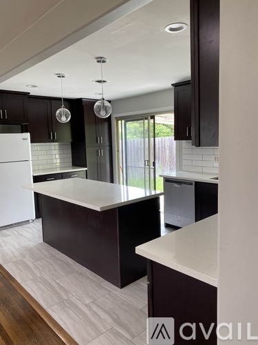 A kitchen with a white fridge and a white island.