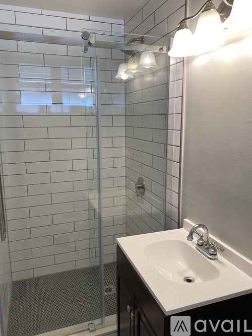 A bathroom with a white sink and a glass shower stall.