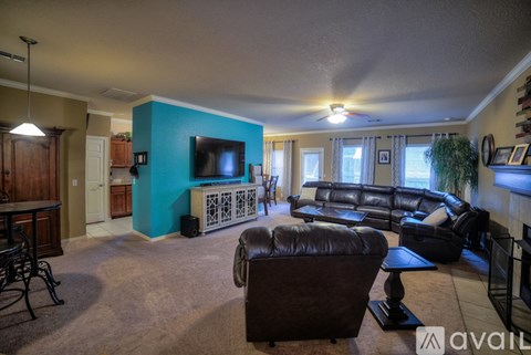 A living room with a brown leather couch and a blue wall.