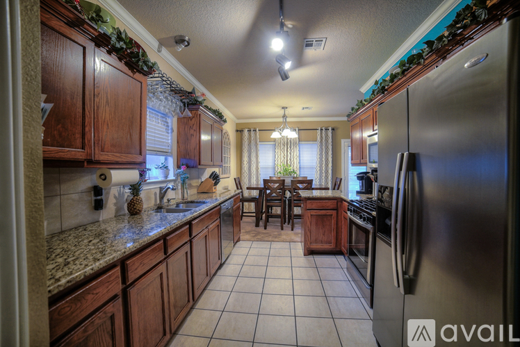 A kitchen with a stainless steel refrigerator and wooden cabinets.
