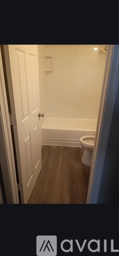 A small bathroom with a toilet and wooden floor.