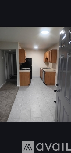 A kitchen with wooden cabinets and a black refrigerator.