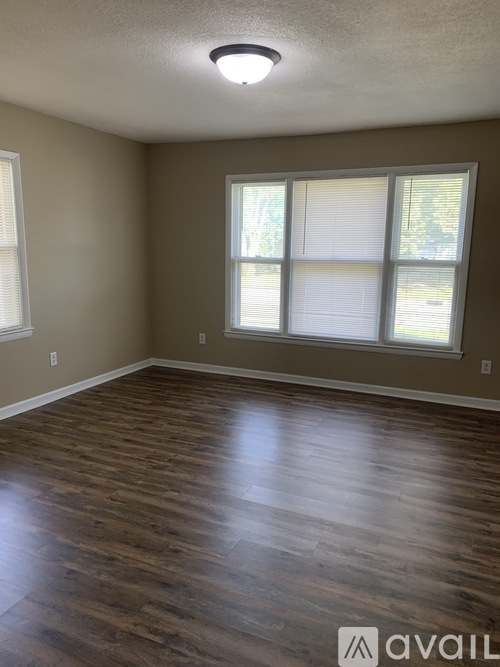 A room with wooden flooring and a window with blinds.