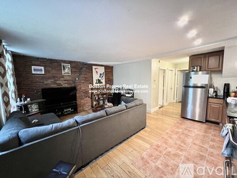 A living room with a grey couch and a fireplace.
