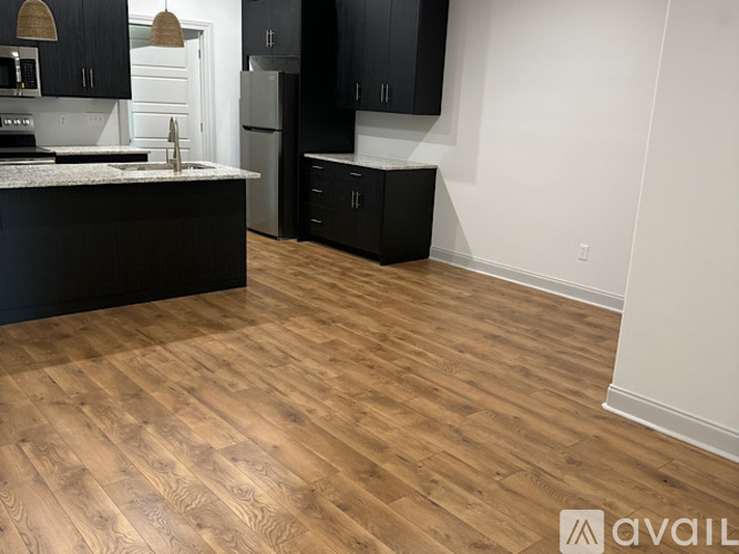 A kitchen with black cabinets and a wooden floor.