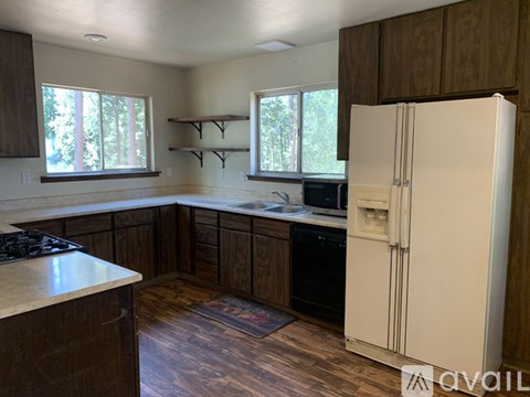 A kitchen with a white refrigerator, wooden cabinets, and a black stove top.