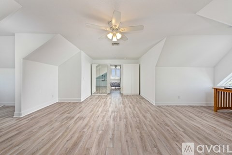 A spacious room with wooden flooring and a ceiling fan.