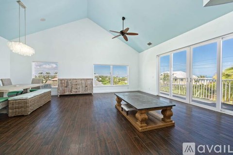 A spacious living room with a large table and a ceiling fan.