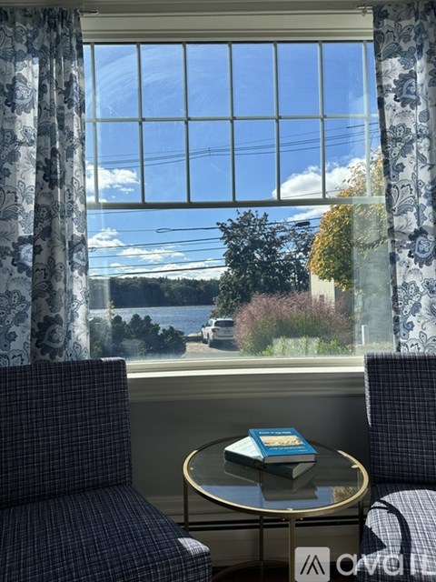 A book is on a table in front of a window with a view of the outside.