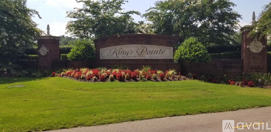A sign that says "King's Pointe" is in front of a green lawn.