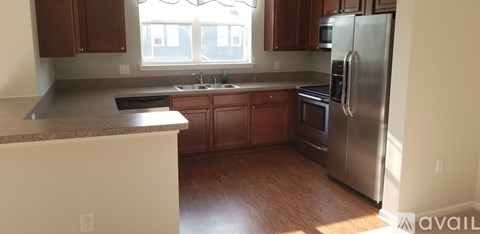 A kitchen with wooden cabinets and a stainless steel refrigerator.