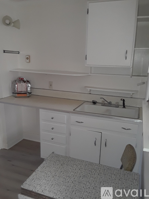 A bathroom with a sink, mirror, and cabinets.
