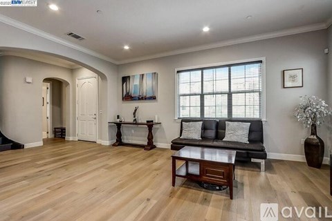 A living room with a black couch, wooden coffee table, and a painting on the wall.