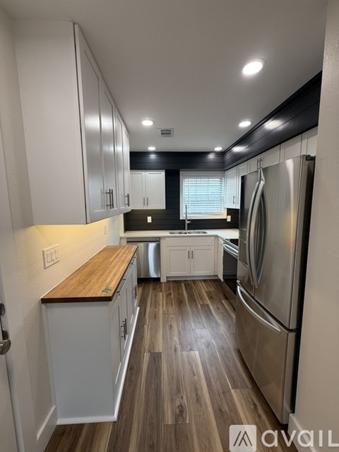 A kitchen with white cabinets and a wooden countertop.