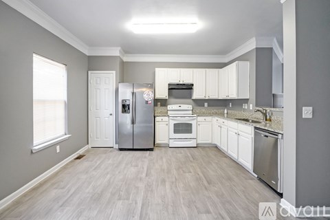 A kitchen with white cabinets and a grey wall.