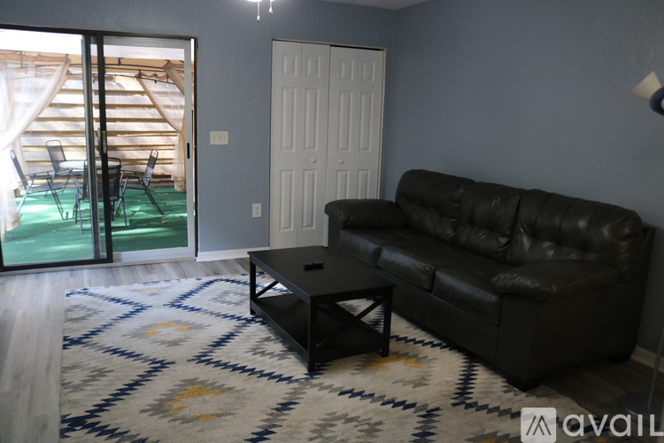 A black leather couch sits in a living room with a rug and a coffee table.