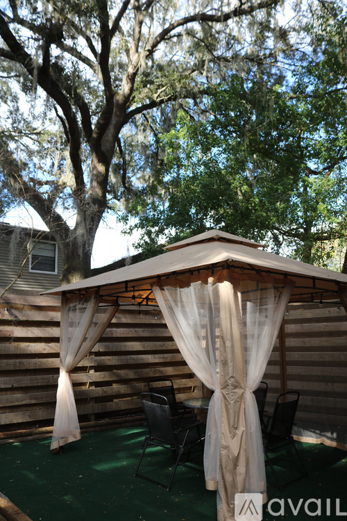 A gazebo with a canopy and curtains is set up in a backyard.