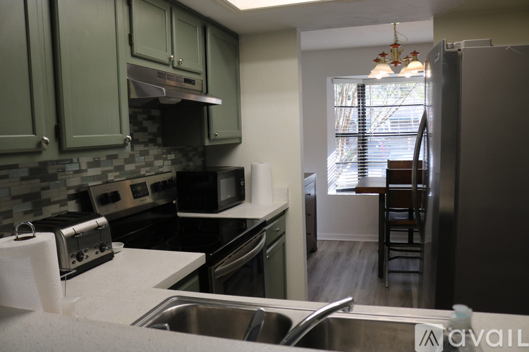 A kitchen with green cabinets and a stainless steel refrigerator.