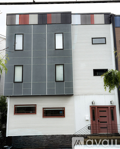 A modern building with a white and grey facade and a red door.