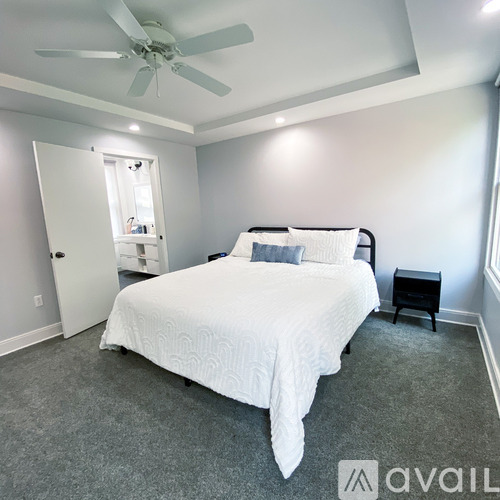 A bedroom with a white bed and a ceiling fan.