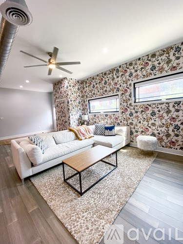 A living room with a white couch and a floral wallpaper.