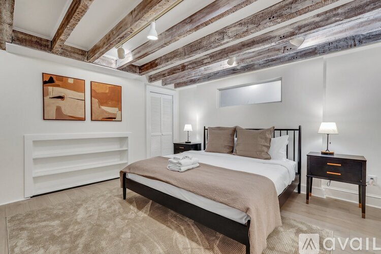 A bedroom with a bed, nightstands, and a painting on the wall.
