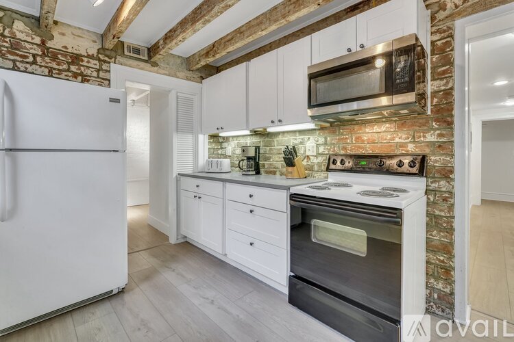 A kitchen with white cabinets and a brick wall.