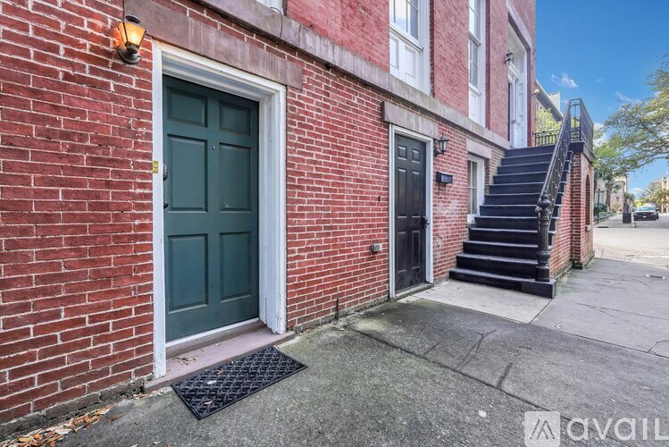 A red brick building with a green door and a black door.