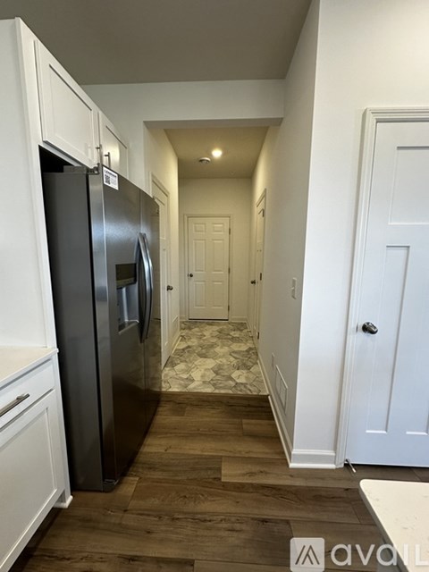 A kitchen with a black fridge and white cabinets.