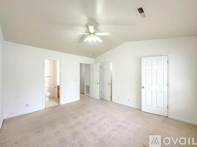 A spacious room with a ceiling fan and carpeted floor.