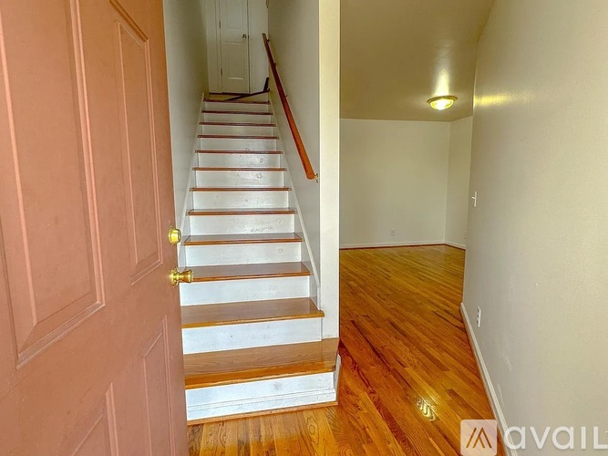 A hallway with a wooden floor and a staircase leading to the second floor.