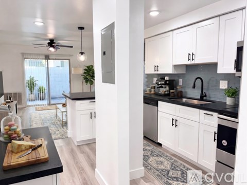 A kitchen with white cabinets and a black countertop.