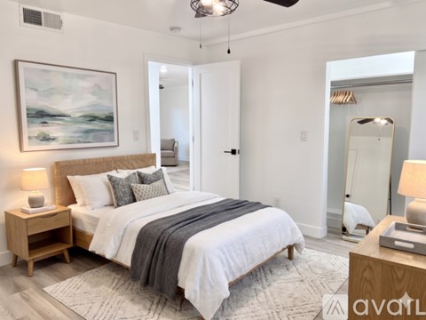 A bedroom with a large bed and a painting on the wall.