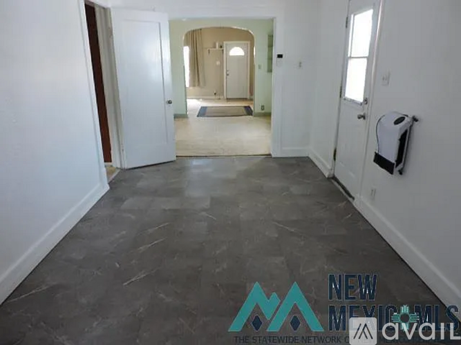 A spacious room with a tiled floor and a toilet paper holder on the wall.