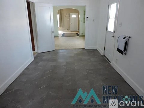 A spacious room with a tiled floor and a toilet paper holder on the wall.