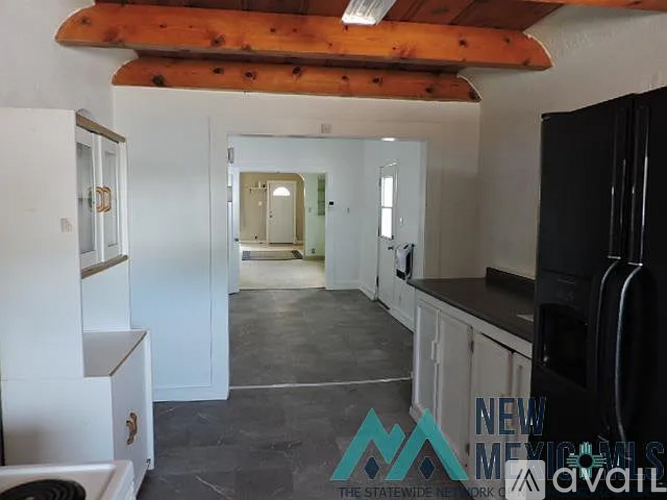 A kitchen with white cabinets and a black fridge.