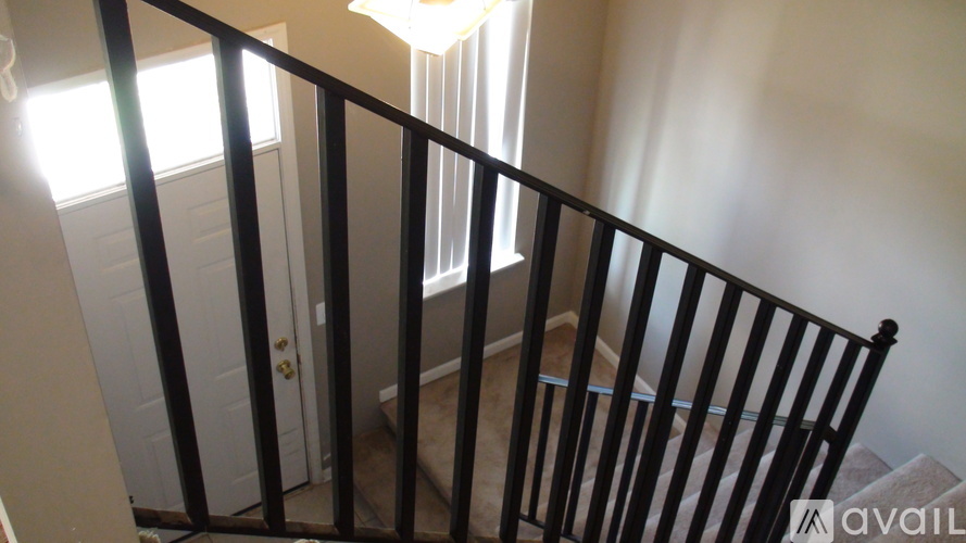 A staircase with a black railing and a white door in the background.