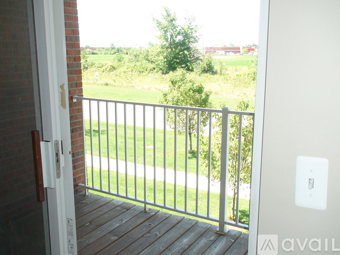 A balcony with a view of a green field and trees.