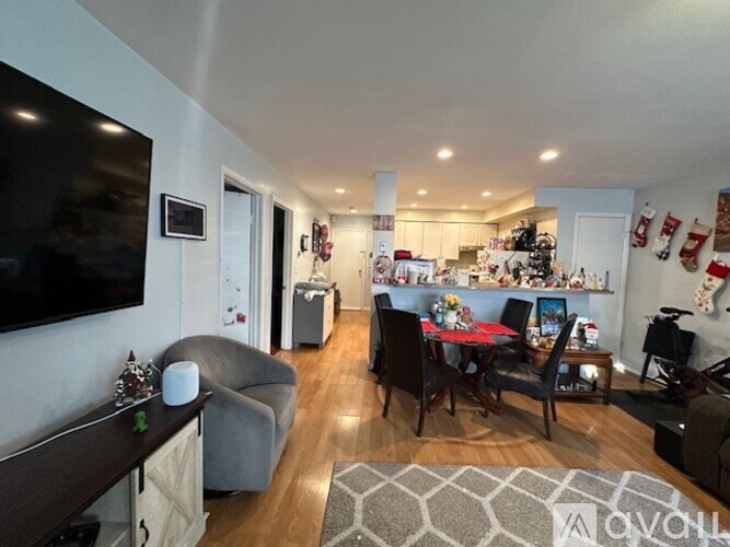 A living room with a grey couch, a wooden table, and a television on the wall.