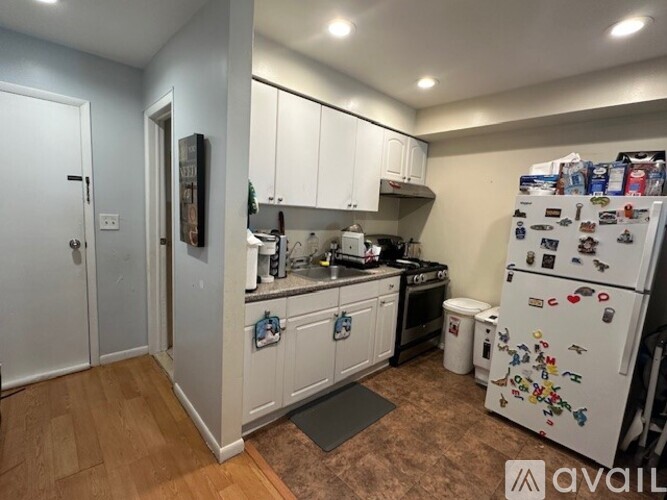 A kitchen with white cabinets and a fridge with magnets.