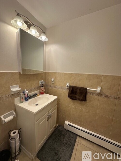 A bathroom with a toilet paper holder, toothbrush holder, and a towel rack.