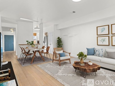 A living room with a white couch, a wooden coffee table, and a dining table with chairs.