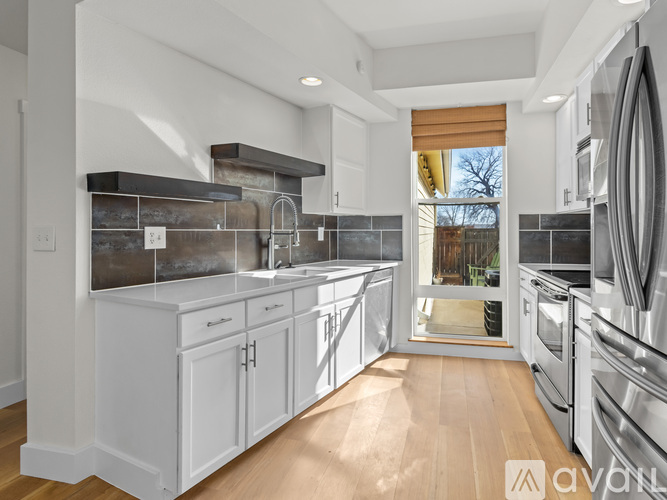 A modern kitchen with white cabinets and stainless steel appliances.